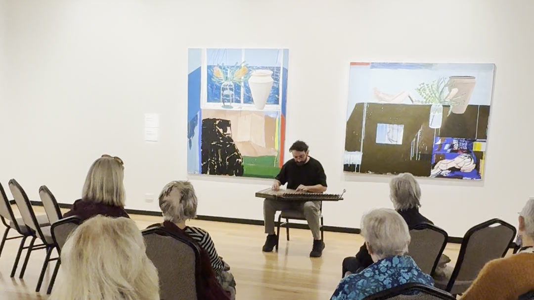 Camille playing a solo qānūn recital in a gallery